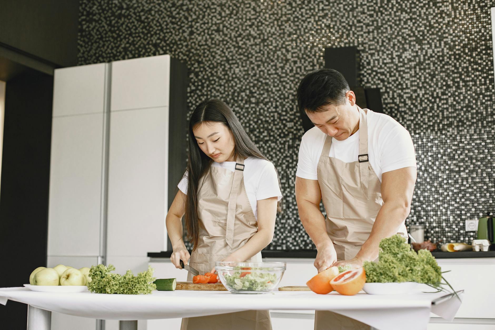 Azjatycka para kroi warzywa i gotuje zdrowy obiad w nowoczesnej kuchni