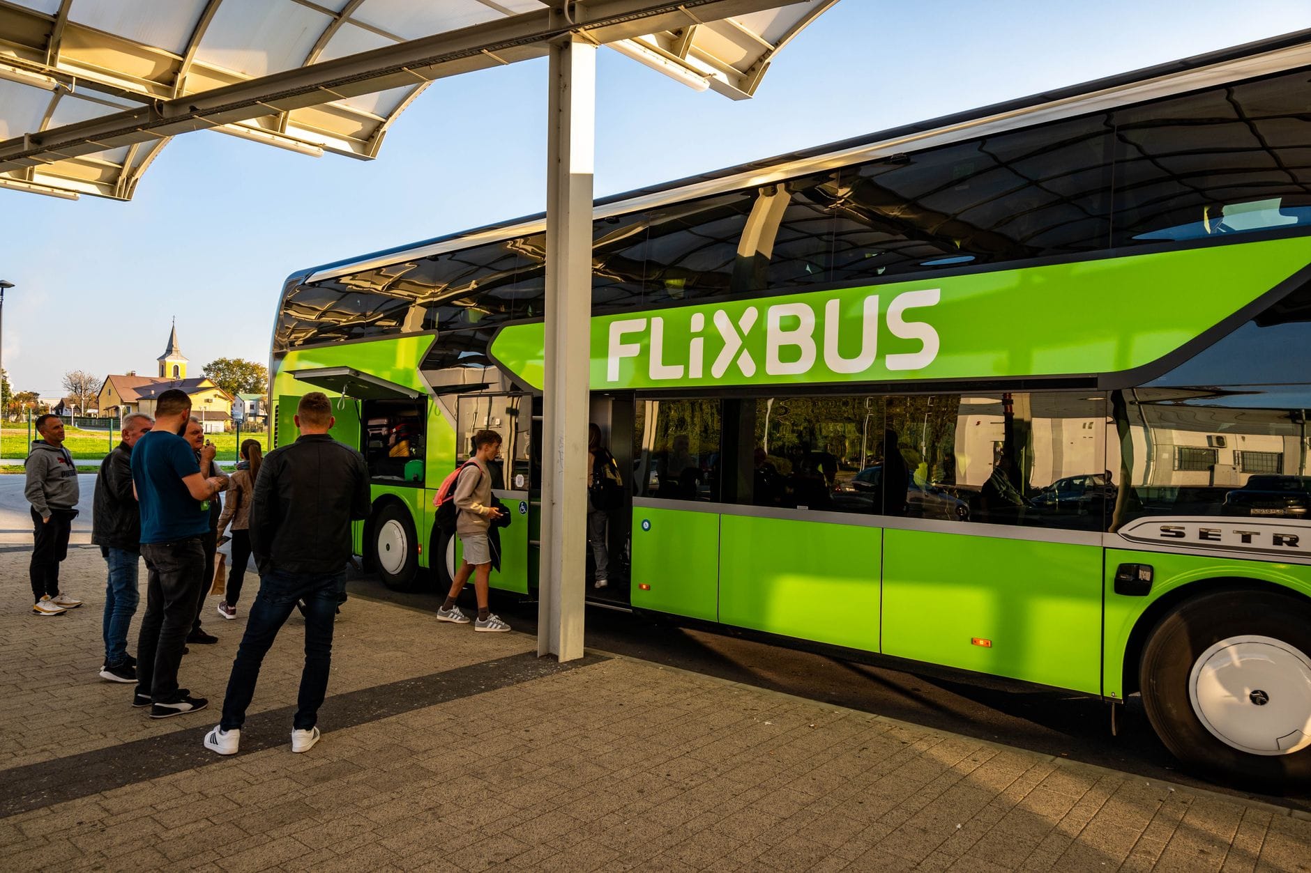 Pasażerowie wsiadają do zielonego autobusu dalekobieżnego FlixBus