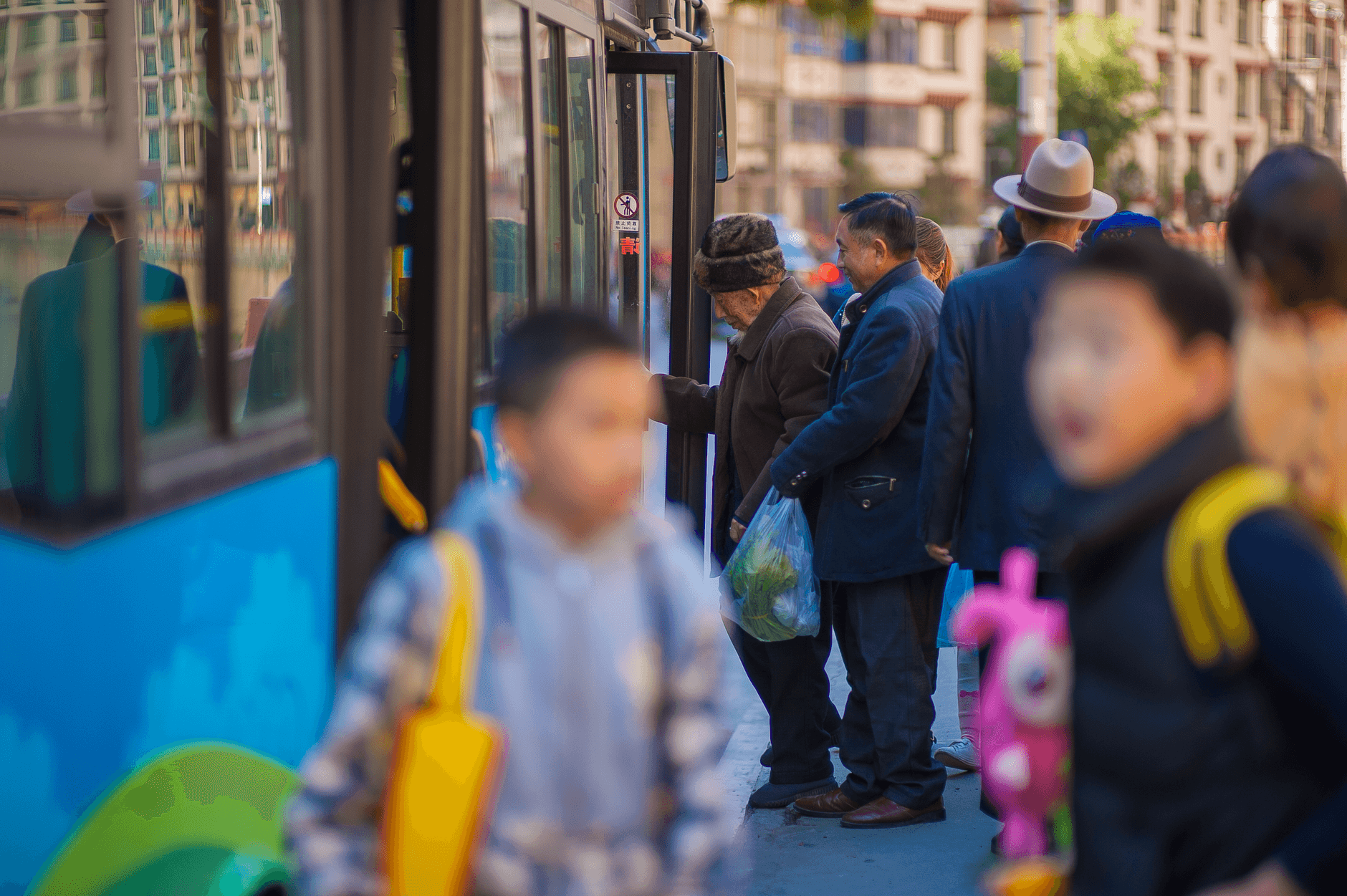 Rodziny z dziećmi wsiadają do autobusu na ruchliwej miejskiej ulicy